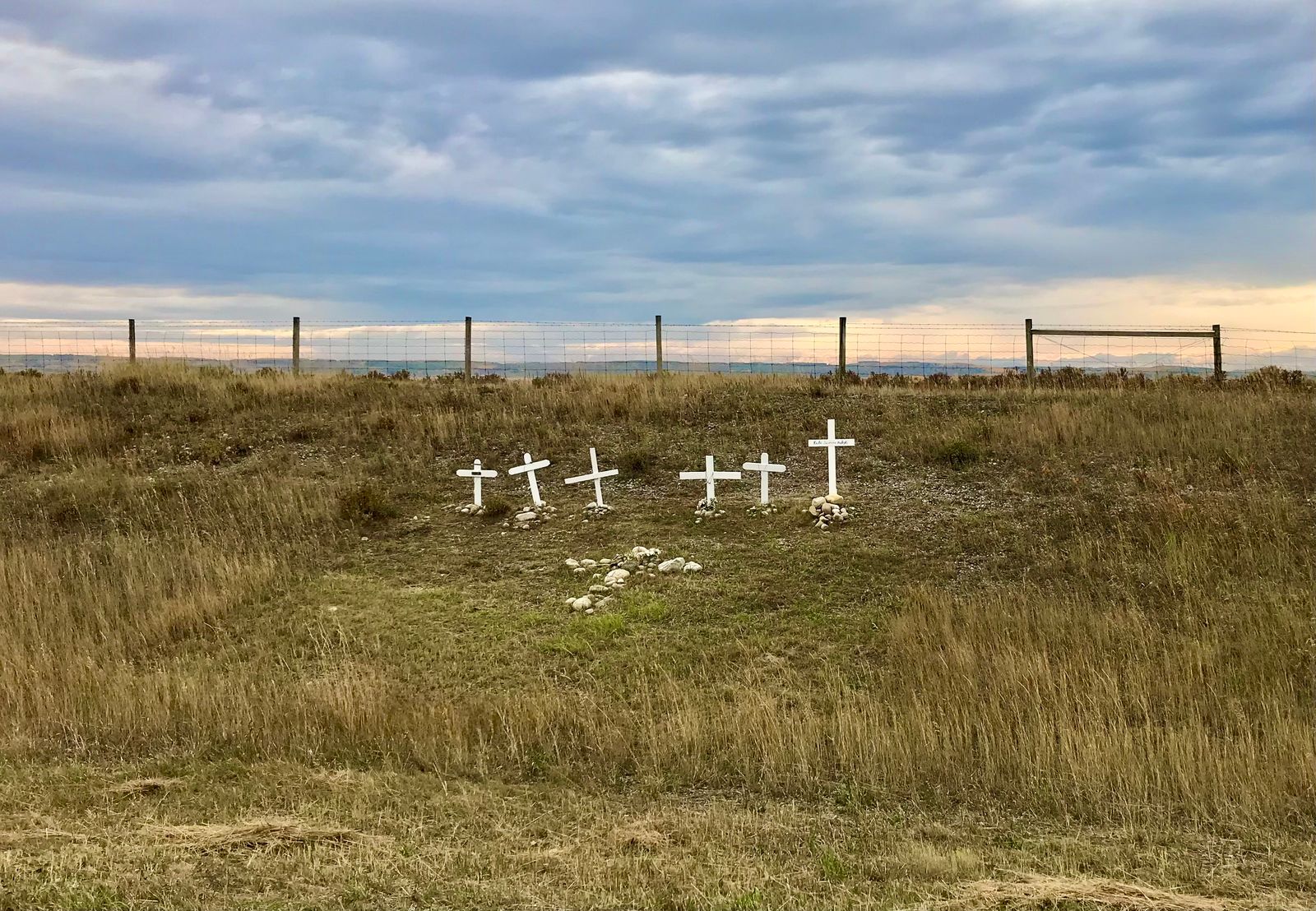 White memorial crosses on an open prairie under a cloudy sky