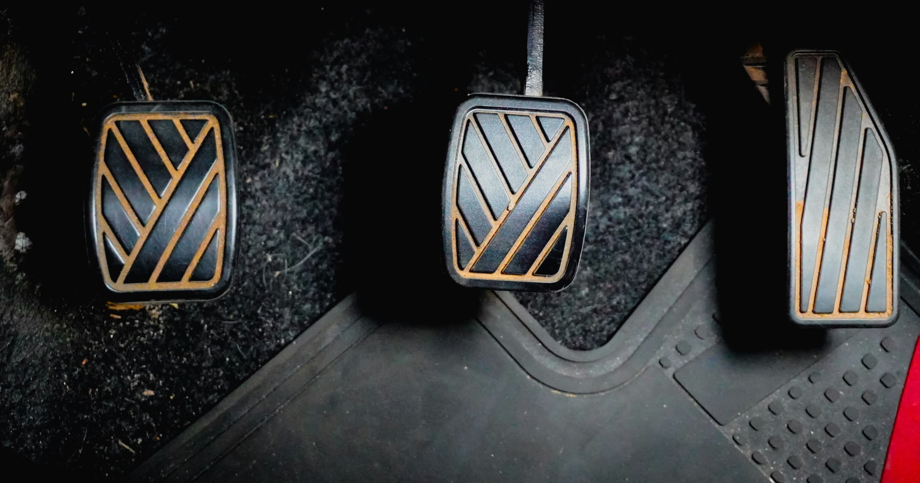Close-up of the clutch, brake, and accelerator pedals in a car footwell