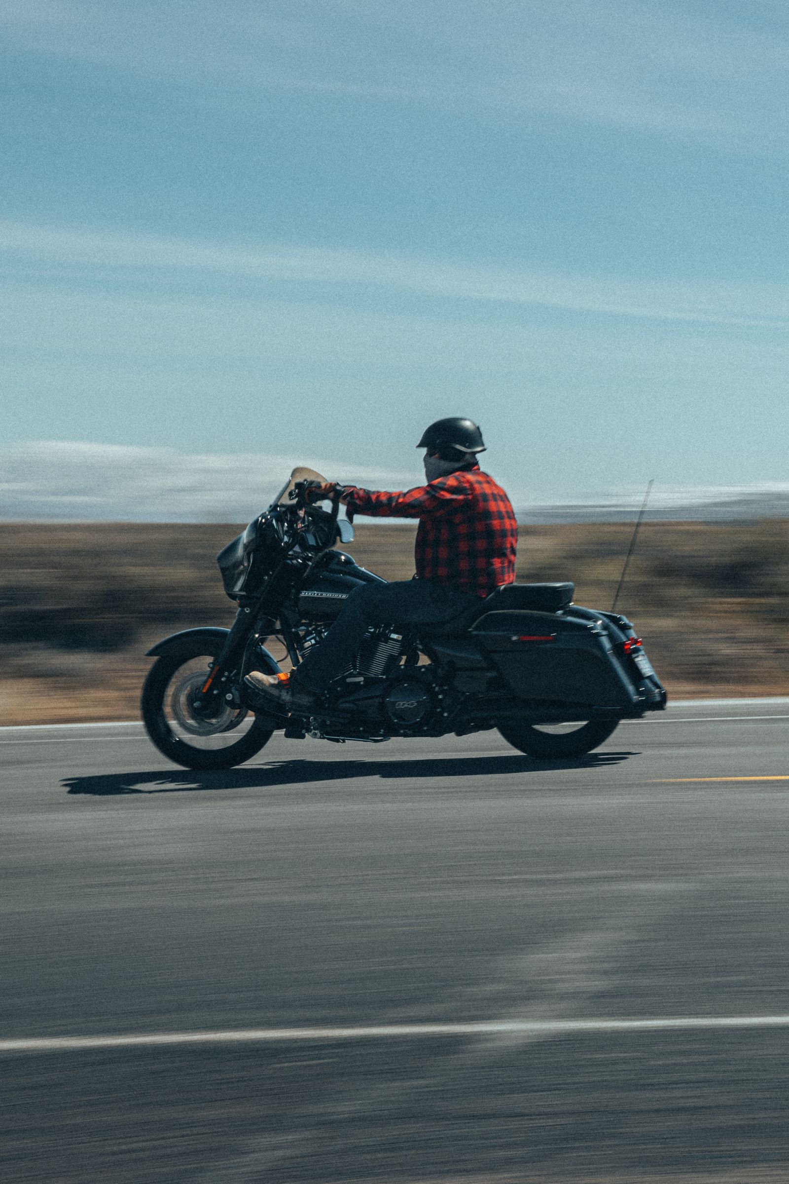 Motorcyclist in a helmet riding a flat, open Texas highway under a wide clear sky