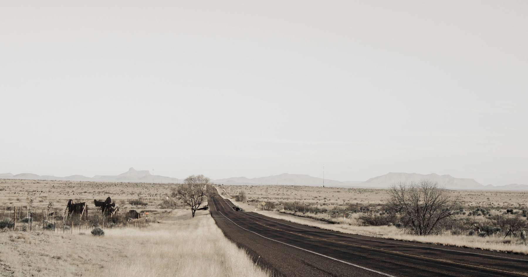 Empty two-lane Texas highway stretching across open plains under a wide, quiet sky