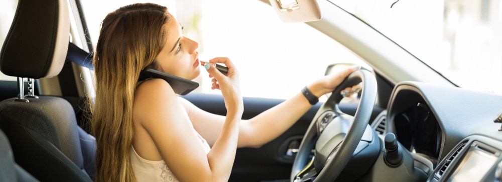 Careless young woman applying make up and talking on the phone while driving